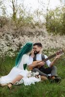 a bearded groom plays a stringed instrument and a girl sits in a spring meadow photo