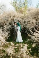 a bearded groom plays and a girl with green hair against the background of blooming spring photo