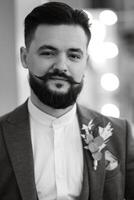 portrait of smiling groom with beard in gray color suit photo