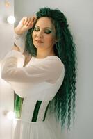 portrait of a bride with green curly hair in the beauty room photo