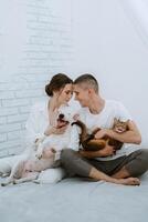 young couple guy and girl in a bright room playing with pets photo