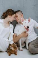 young couple guy and girl in a bright room playing with pets photo