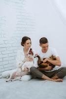 young couple guy and girl in a bright room playing with pets photo