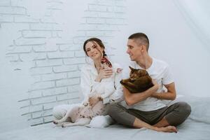 young couple guy and girl in a bright room playing with pets photo