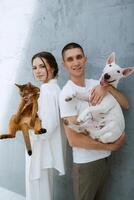 young couple guy and girl in a bright room playing with pets photo