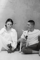 young couple guy and girl in a bright room playing with pets photo