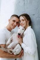 young couple guy and girl in a bright room playing with pet photo