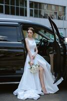 bride with a black car near a glass skyscraper photo