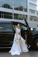 bride with a black car near a glass skyscraper photo