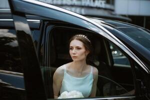 bride with a black car near a glass skyscraper photo