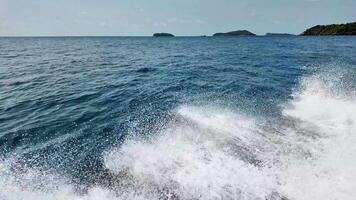 panoramico oceano spray a partire dal un' in movimento barca con tropicale isole nel il sfondo, ideale per viaggio e estate vacanza temi video