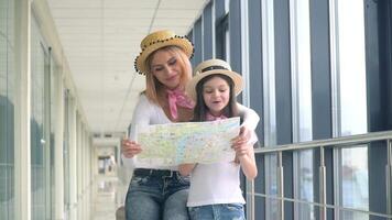 lindo mulher com pequeno menina segurando uma turista mapa às a aeroporto video