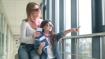 Female and little girl holding passports and airline boarding pass tickets. Boarding pass and passport at airport. Girl shows on an airplane arriving video