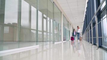 pasajeros con maletas caminando en el terminal aeropuerto. mujer y pequeño niña con equipaje yendo en el aeropuerto video