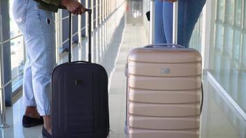 Two african american girls travelers are carrying their luggage and moving over lounge of terminal, back view. People are preparing to boarding and departing video