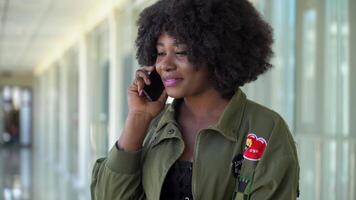 africain américain fille sont attendre à embarquement et départ à le aéroport et parlant sur le téléphone video