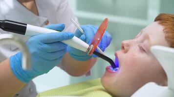 femmina dentista nel opera. poco ragazzo a ricezione a dentista nel dentale sedia. pediatrico odontoiatria video