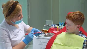 A female dentist brushes fake jaws and teaches little boy to brush teeth video