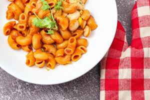 Macaroni with tomato sauce and parsley in a white bowl Served on a white plate, top view photo