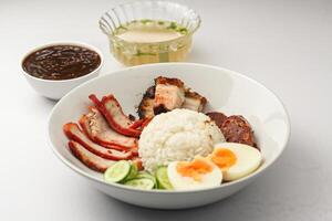 Red Pork and Crispy Pork on Rice Served with Chinese sausage, cucumber, boiled egg. and boiled bone soup, red pork and crispy pork on rice It is a popular food in Thailand. photo