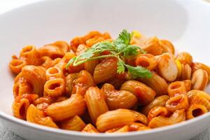 macarrones con tomate salsa y perejil en un blanco cuenco servido en un blanco plato foto