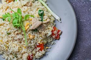 Fried rice with pork and vegetables in a plate on the table photo