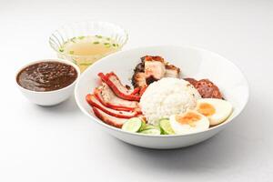 Red Pork and Crispy Pork on Rice Served with Chinese sausage, cucumber, boiled egg. and boiled bone soup, red pork and crispy pork on rice It is a popular food in Thailand. photo