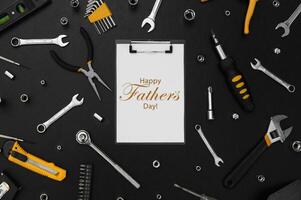Lettering Happy Father's Day with many different tools for repair work on a black table. photo