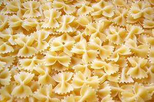 A lot of pasta in the shape of a butterfly on the table as a background. photo