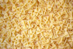 A lot of pasta in the shape of a butterfly on the table as a background. photo