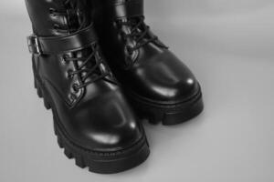 Black high leather boot on a grey background. photo