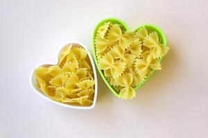 Butterfly shaped pasta stacked in a heart shape on the table. photo