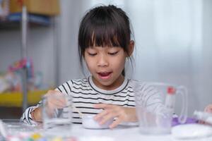 linda pequeño niña haciendo bricolaje yeso y pintura a hogar. niños pintar en yeso esculturas con familia en día festivo. imaginación y creatividad actividades. foto