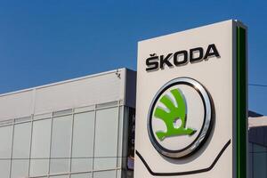 Green logo of car brand skoda on on promotional stand at sunny day in front of a dealership building. photo