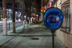 TULA, RUSSIA - APRIL 22, 2017 blue payphone post at night city sidewalk with selective focus photo