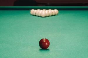 They play pool on a green table.The balls are placed in a triangle on the table. photo