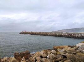 Ocean shore in stormy winter weather. Waves with splashes crash against the pier. photo