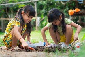 Little girl planting plants in pots from recycled water bottles in the backyard. Recycle water bottle pot, gardening activities for children. Recycling of plastic waste photo