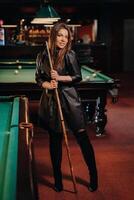 A girl with a cue in her hands is standing in a billiard club.Russian billiards photo