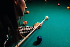 un niña en un sombrero en un de billar club con un señal en su manos golpes un pelota.jugando billar foto