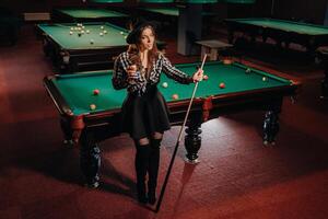 A girl in a hat in a billiard club with a cue in her hands.billiards Game photo
