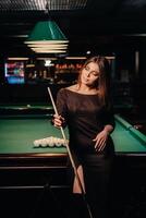 A girl in a hat in a billiard club with a cue in her hands.Pool Game photo