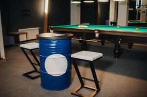 table and two chairs near the green-covered billiard table with balls in the billiard club photo