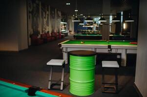 table and two chairs near the green-covered billiard table with balls in the billiard club photo