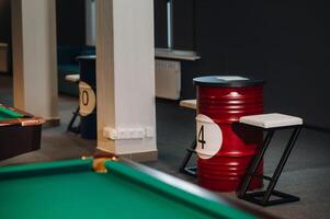 table and two chairs near the green-covered billiard table with balls in the billiard club photo