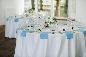 The festive table is decorated in light colors with blue napkins and flowers without food photo