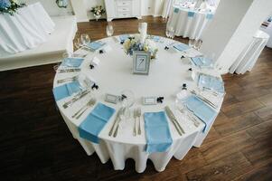 The festive table is decorated in light colors with blue napkins and flowers without food photo