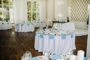 The festive table is decorated in light colors with blue napkins and flowers without food photo