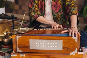 Hands of a woman sitting on the floor and playing the harmonium during the practice of kundalini yoga photo