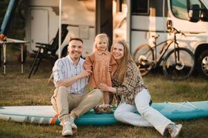 a young family is sitting on a sup board next to their mobile home photo